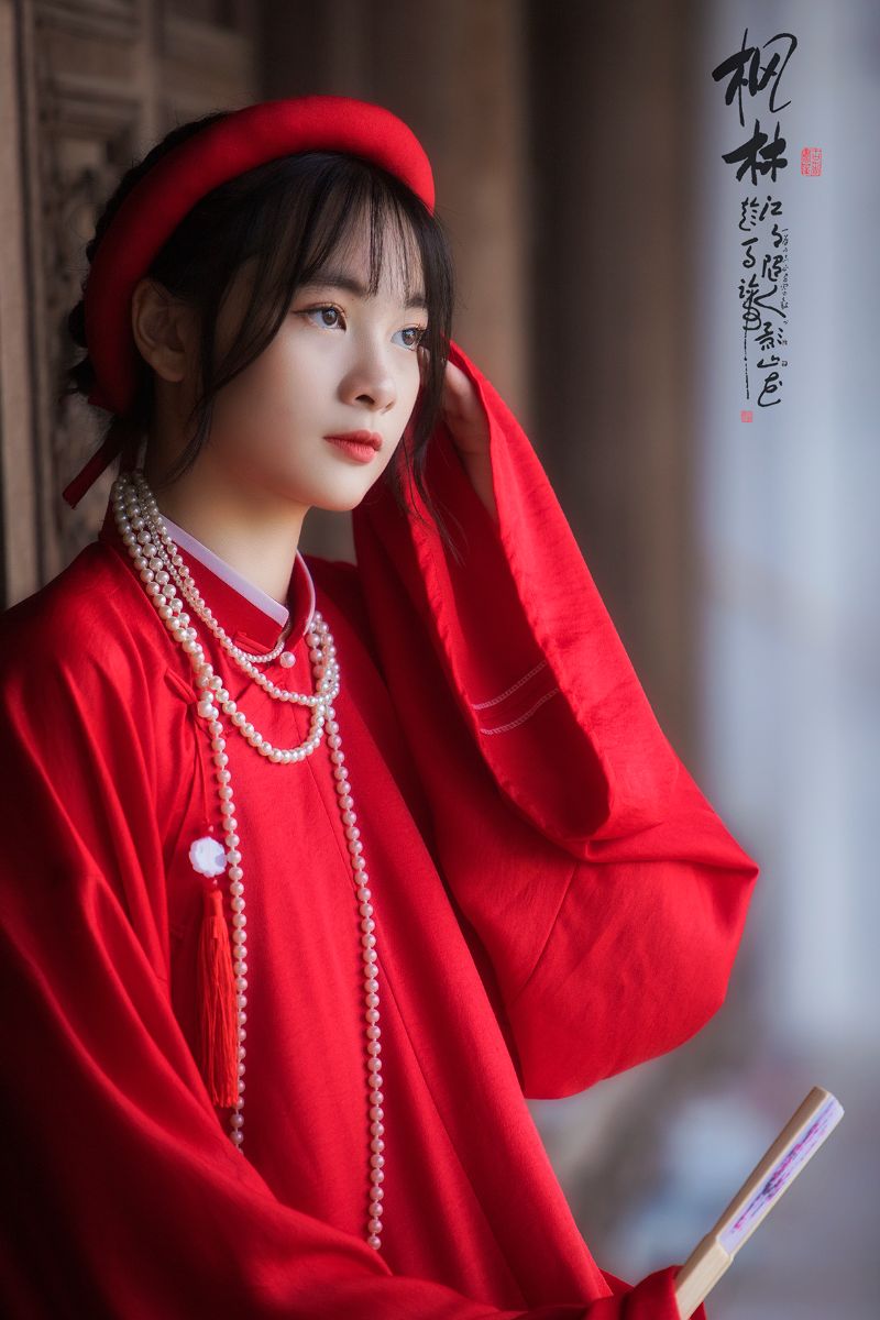 cô gái trẻ mặc áo dài đỏ đưa tay vuốt tóc